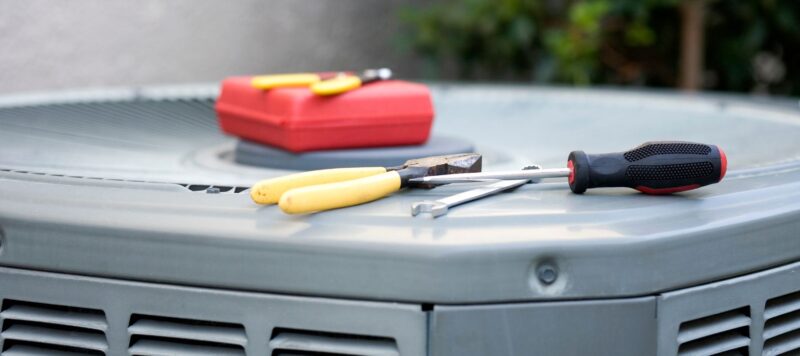 repair tools resting on top of an outdoor air conditioning unit
