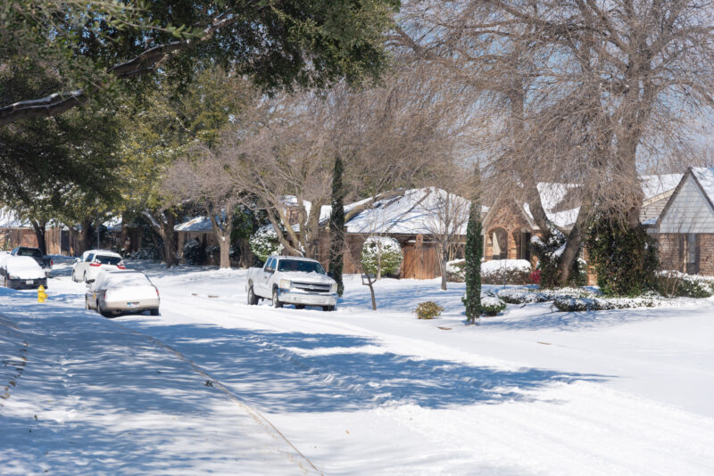 a neighborhood street in fort worth covered in snow after a winter storm