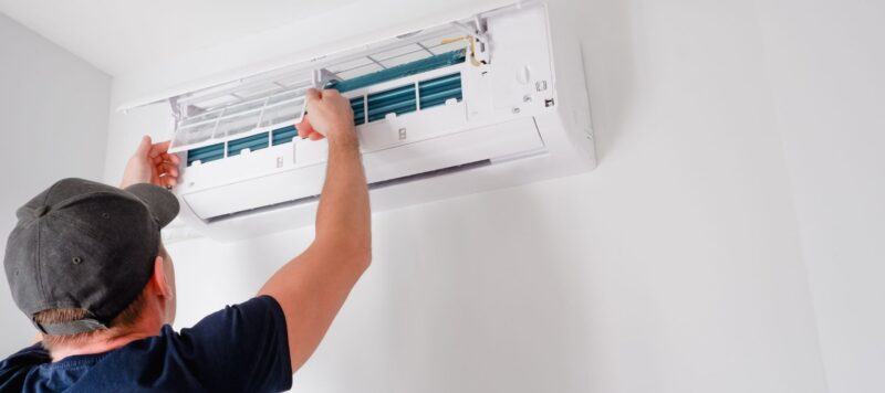 a service technician performing maintenance on an interior ductless ac unit