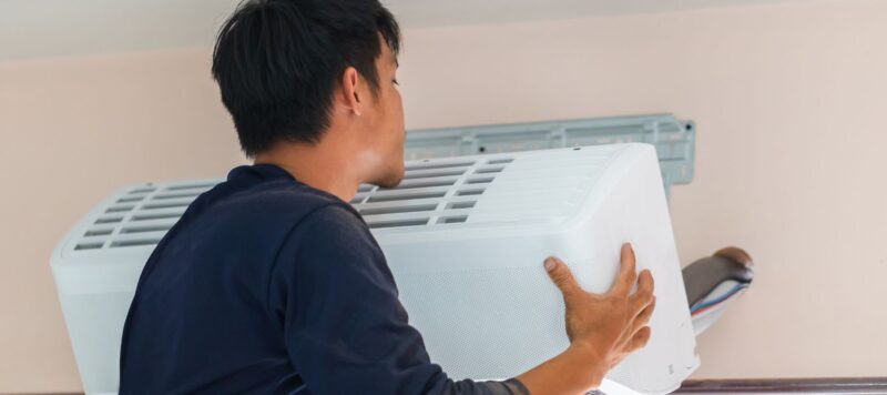 an ac technician installing an indoor ductless ac system to the wall of a home