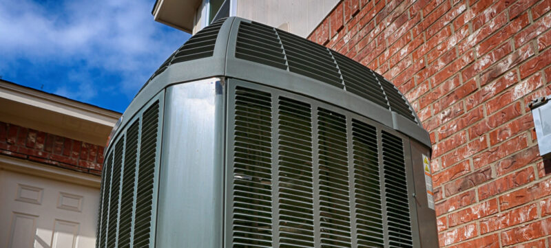 high efficiency black ac unit installed outside of a texas home with red brick