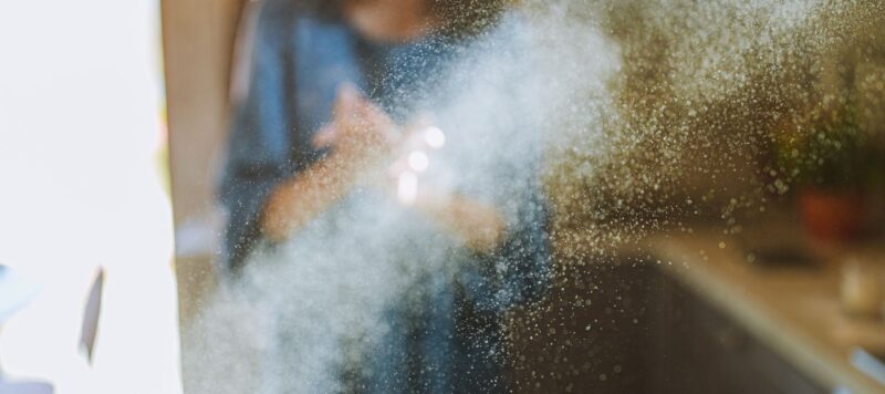 a beam of sunlight showing dust mites floating next to a woman inside her home