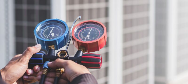 close up of technician hands holding red and blue gauges